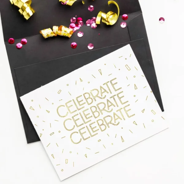 White birthday card with gold foil lettering Celebrate text and small graphics